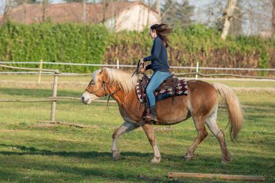 Full length of a man riding horse on field