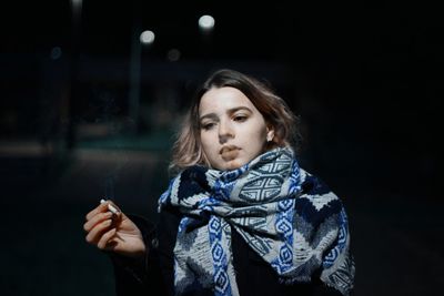 Portrait of a beautiful young woman holding camera at night