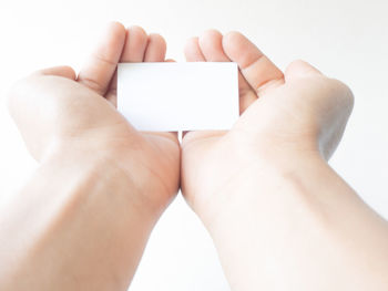 Midsection of woman holding hands over white background