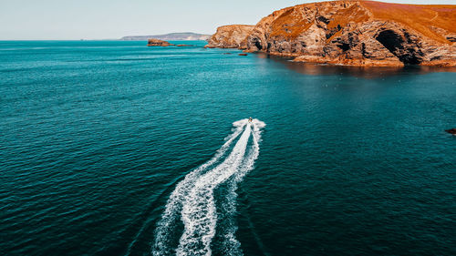 The jet ski runs in the direction of the rock on turquoise water. aerial view