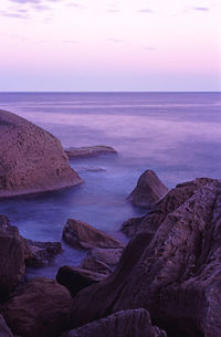 Scenic view of rocky shore and sea against sky