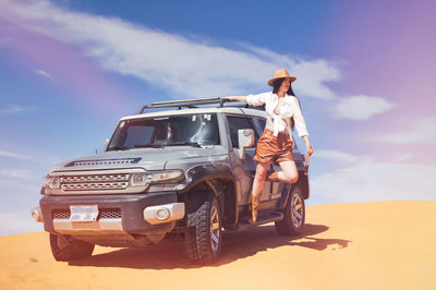 Low angle view of woman standing by car