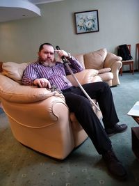 Full length of man sitting on sofa at home