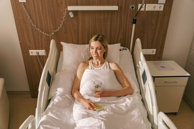 Portrait of woman sitting on bed at home