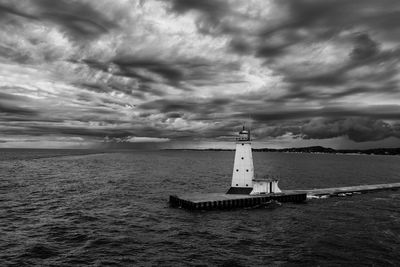 Lighthouse by sea against sky