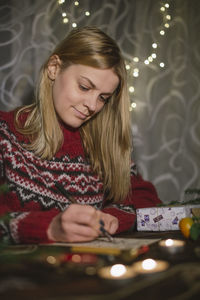 Midsection of woman holding christmas lights at home