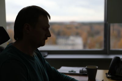 Portrait of young man looking through window