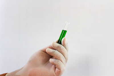 Close-up of hand holding paper over white background