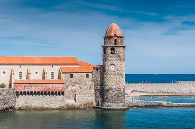 Tower of building by sea against sky