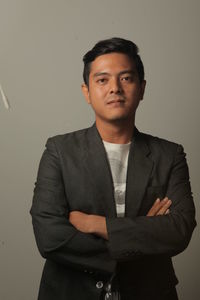 Portrait of young man standing against gray background