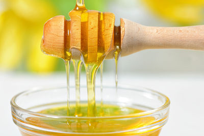 Close-up of honey pouring from dipper in bowl on table