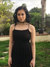 Beautiful young woman in black dress standing at park