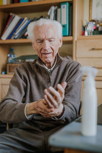 Senior man using hand sanitizer at home