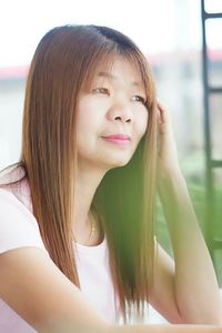 Thoughtful mature woman looking away while sitting at backyard