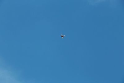 Low angle view of airplane flying against clear blue sky