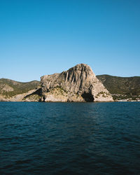 Scenic view of sea and mountains against clear blue sky