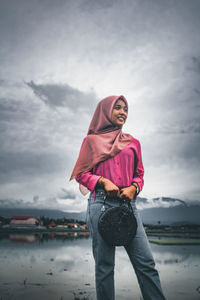 Woman looking away while standing against sky