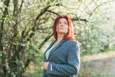 Young woman standing against trees