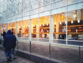 Rear view of people walking on glass window