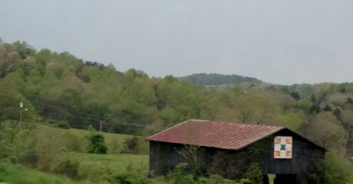 House amidst trees and mountains against sky