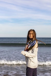 Woman standing at beach against sky