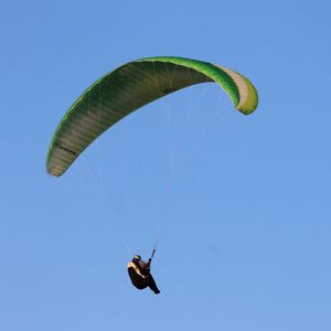 Low angle view of person paragliding against clear blue sky