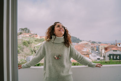 Portrait of smiling young woman standing against sky