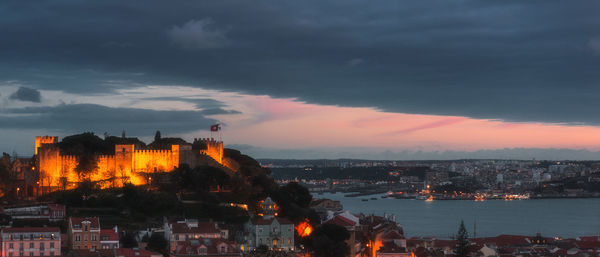 Buildings by sea against sky at dusk