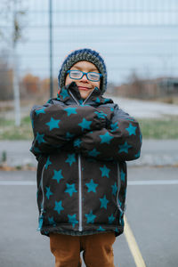 Portrait of boy with arms crossed standing on road