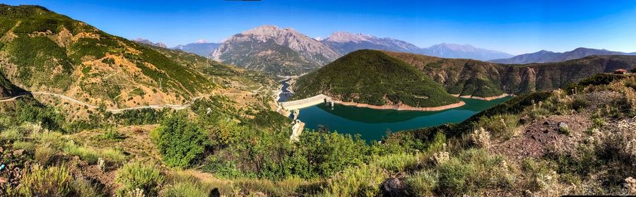 Panoramic view of plants and mountains against blue sky