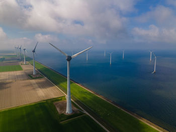 Wind turbines on land against sky