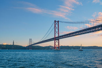 View of 25 de abril bridge with tourist yacht boats. lisbon, portugal