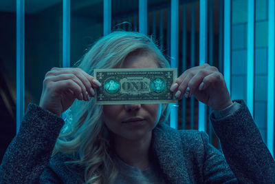 Young woman holding money in front of face