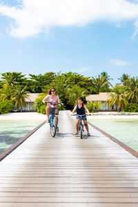 Mother and son riding their bikes on a walkway in the maldives