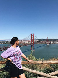 Woman standing on bridge against clear blue sky