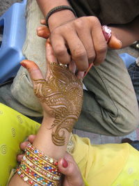 High angle view of man drawing henna tattoo on woman hand