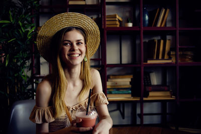 Portrait of smiling young woman sitting at table