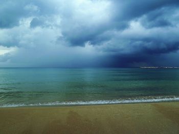 Scenic view of beach against cloudy sky