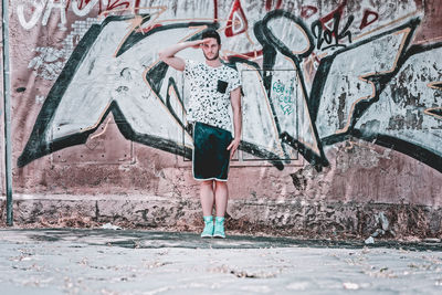 Full length of woman standing against graffiti wall