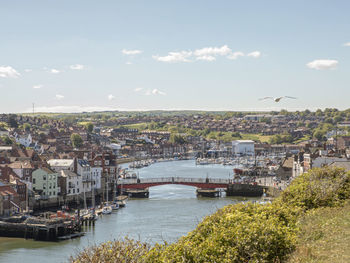 Scenic view of river by buildings against sky