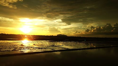 Scenic view of lake against dramatic sky during sunset