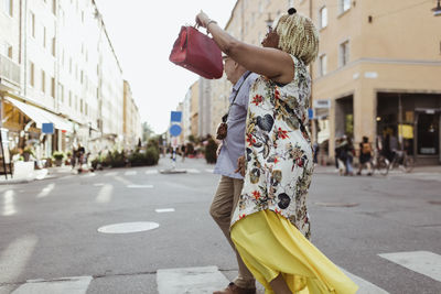 Senior woman pointing while exploring with man in city