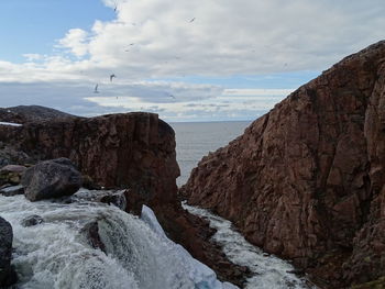 Rock formations by sea against sky