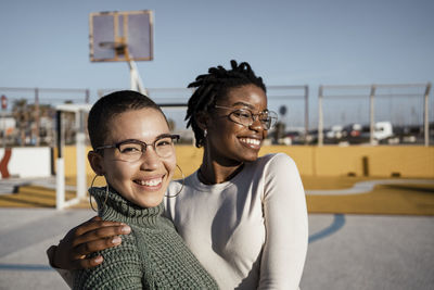 Young women smiling while standing at basketball court