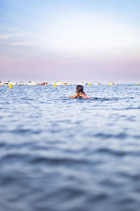 People swimming in sea against sky