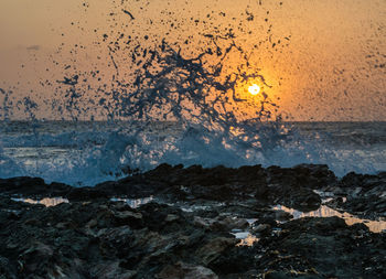 Sea waves splashing on rocks during sunset