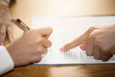 Midsection of man holding smart phone on table