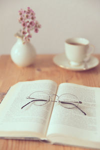 High angle view of eyeglasses on book with tea cup on table