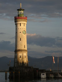 Lighthouse by building against sky