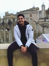 Portrait of smiling man sitting against building